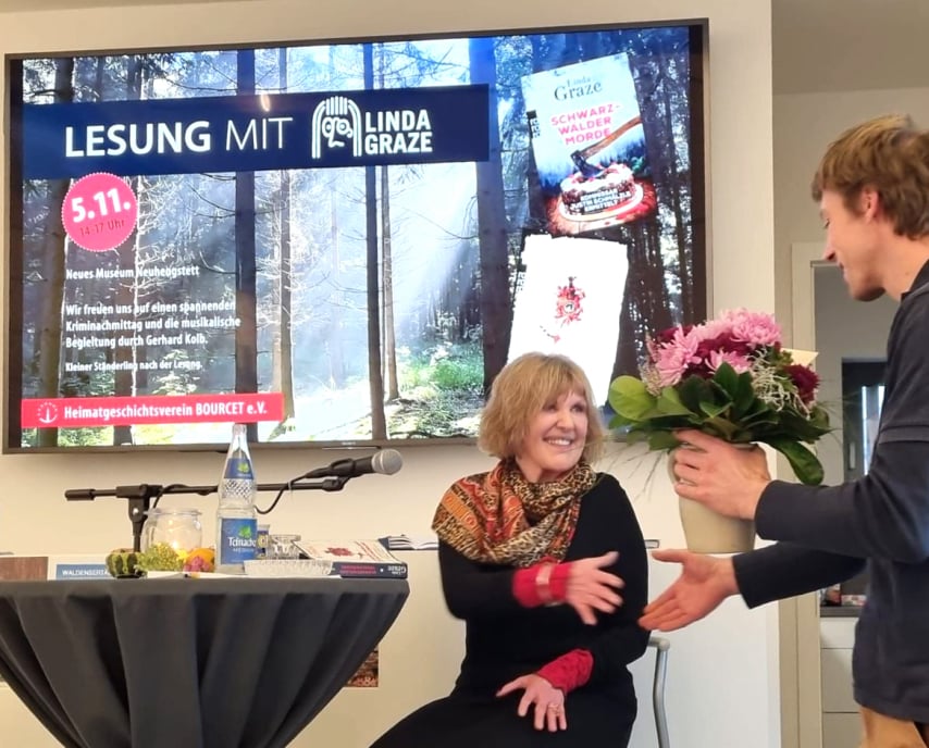 Übergabe eines Blumenstraußes an die Autorin Linda Graze